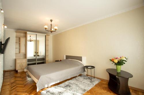 尼古拉耶夫Уютная квартира в центре的一间卧室,配有一张床,桌子上放着花瓶