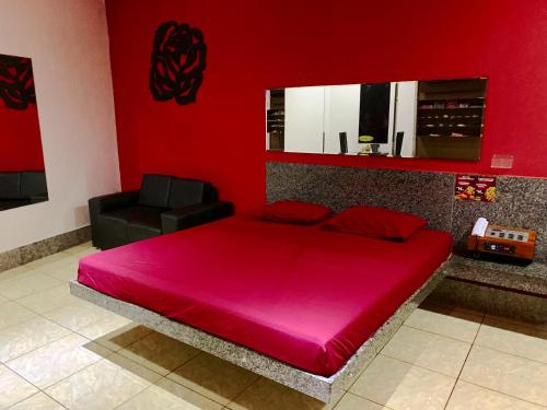 福塔莱萨Motel Emoções (Adults Only)的红色卧室设有一张大床和一张黑椅