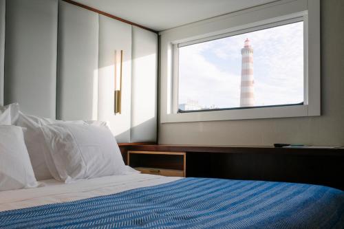 阿威罗Costa do Sal Hotel Boat Lounge的一间卧室配有一张床铺,透过窗户可以看到灯塔