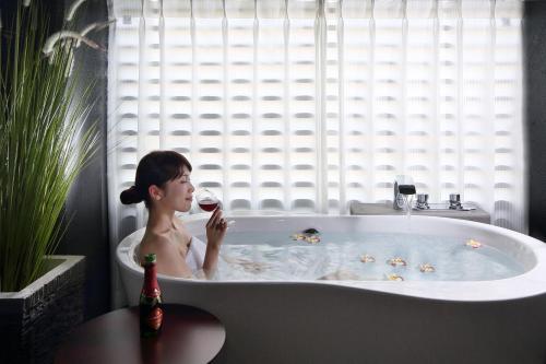 鹿儿岛鹿儿岛天文馆门酒店的坐在浴缸里喝一杯葡萄酒的女人