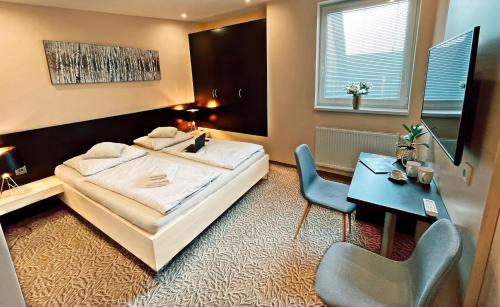科希策Hotel Zlaté Košice的卧室配有1张床、1张书桌和1张桌子及椅子