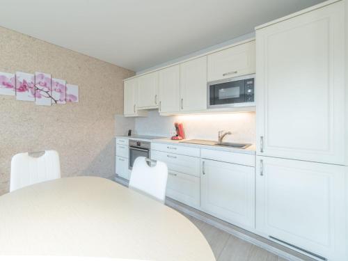 米斯堡Apartment Maria Ter Duyne II by Interhome的厨房配有白色橱柜、桌子和水槽。