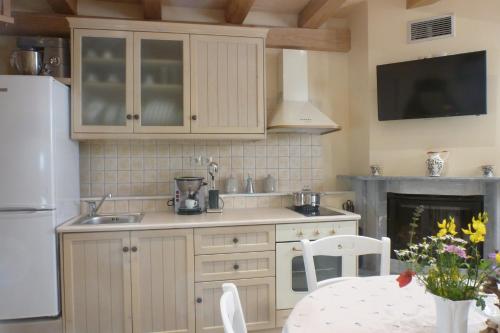 AvgonymaTo Petradi的厨房配有白色橱柜、桌子和壁炉。