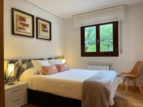 埃利松多Apartamento Baztán的一间卧室配有一张带两盏灯的床和一扇窗户。