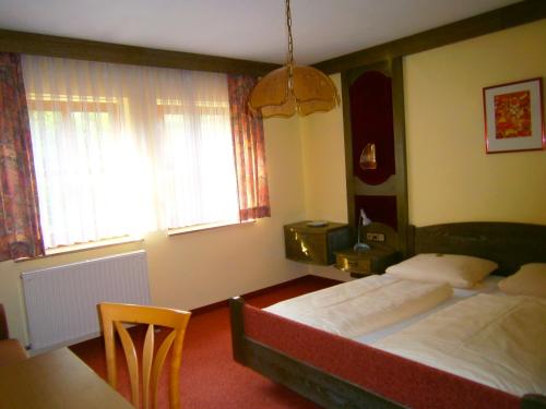 欧波楚巴赫德里林登旅馆的一间卧室设有两张床、一张桌子和两个窗户。