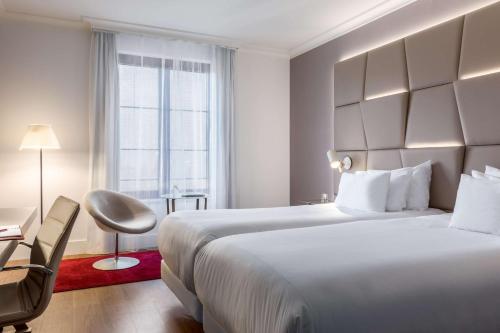 布鲁塞尔布鲁塞尔大萨布隆NH酒店的酒店客房设有一张白色大床和一个窗户。