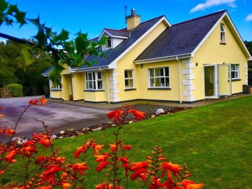 格伦加里夫Rugged Glen Accommodation的院子里的黄色房子,有红色的鲜花