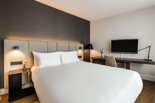 阿姆斯特丹阿姆斯特丹卡兰萨NH酒店的酒店客房设有一张大床和一台电视。