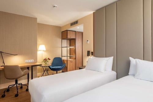 汉诺威NH Hannover的酒店客房配有两张床和一张书桌