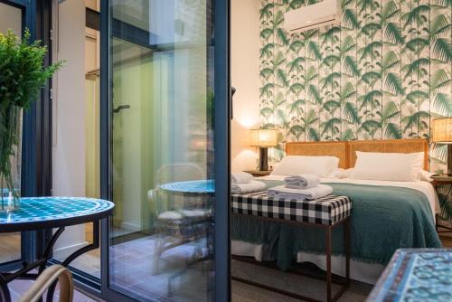 塞维利亚La Casa del Pintor Apartments的一间设有床、桌子和玻璃门的房间