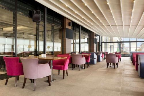 埃拉泽Ramada By Wyndham Elazığ的餐厅设有粉红色的椅子和桌子以及窗户。