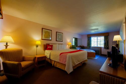 尤里卡斯普林斯Hotel O Eureka Springs - Christ of Ozark Area的配有一张床和一把椅子的酒店客房