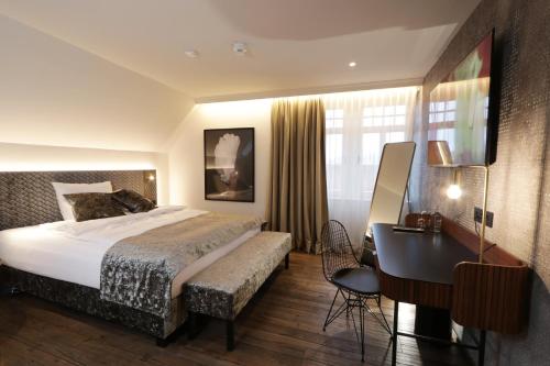布亨REINHARDTs HOTEL的酒店客房配有一张床、一张书桌和一张书桌。