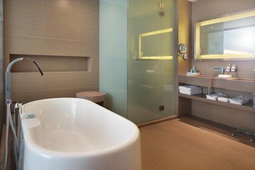马六甲Noble Resort Hotel Melaka的带浴缸和玻璃淋浴间的浴室。