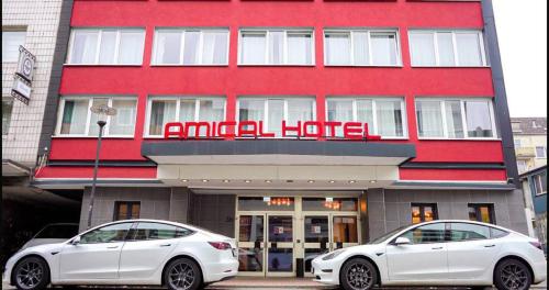 哈根Amical Hotel Hagen - Am Hauptbahnhof的停在酒店门前的两辆白色汽车