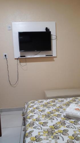 福塔莱萨Pousada Restaurante Sol de Liz的卧室设有壁挂式电视和床。
