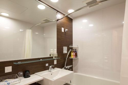 宫崎Comfort Hotel Miyazaki的一间带水槽、浴缸和镜子的浴室
