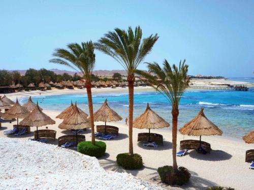 库塞尔Movenpick Resort El Quseir的海滩上拥有遮阳伞和棕榈树,还有大海