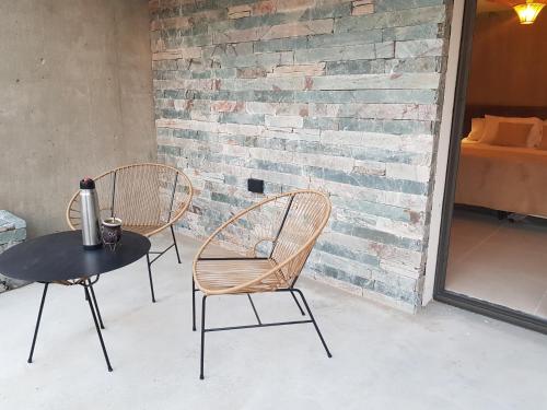 米娜克拉韦罗Favre Suites的砖墙旁的两把椅子和一张桌子