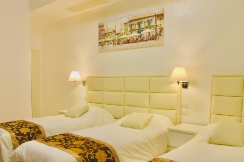 佛罗伦萨Hotel 900 Toscana的酒店客房设有两张床,墙上挂有绘画作品
