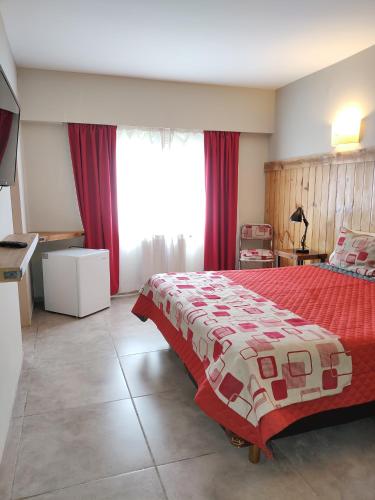 圣卡洛斯-德巴里洛切Hostal El Korú的一间卧室配有一张大床,铺有红白毯子