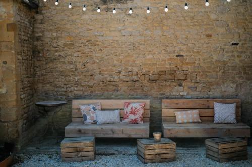 Le Fresne-CamillyLe Domaine de l'Hostellerie的靠在砖墙边的木凳和枕头