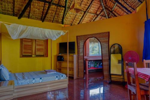阿姆巴托洛阿卡Colibri Lodge的一间卧室设有黄色的墙壁、一张床和镜子