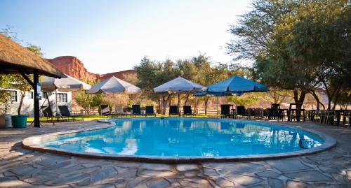 索利泰尔Namib Desert Camping2Go的一个带遮阳伞和桌椅的游泳池