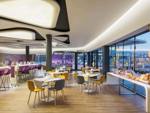 韦切什布达佩斯机场宜必思尚品酒店的餐厅设有桌椅和窗户。