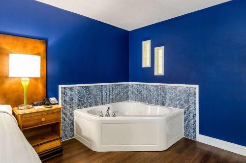 锡康克Clarion Hotel Seekonk - Providence的蓝色的浴室,配有白色浴缸,位于床边
