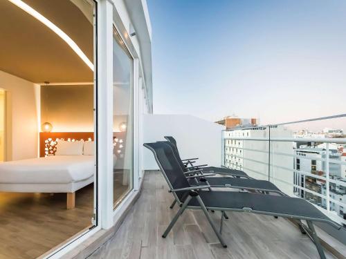 里斯本Ibis Styles Lisboa Centro Marquês de Pombal的客房设有带一张床和椅子的阳台。