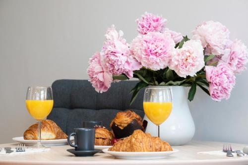 索波特Sopot RIVOLI Apartments by Renters的一张桌子,上面放着两杯橙汁和一瓶粉红色的花