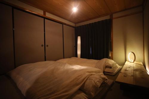 下吕市コミュニティカフェ民泊つむぎ的卧室配有一张带灯的白色大床