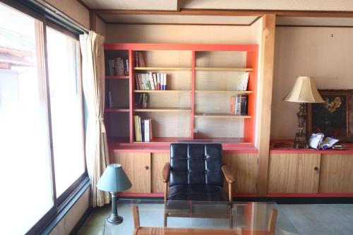 下吕市コミュニティカフェ民泊つむぎ的客厅配有椅子和书架
