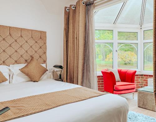 克劳利Trivelles Waterhall Country Gatwick Hotel & airport parking的一间卧室配有一张床、一张红色椅子和一个窗户