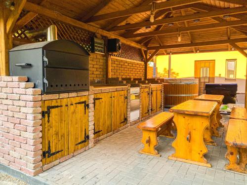 TiszabábolnaBárdos Vendégház的一个带木长椅和烧烤架的户外厨房