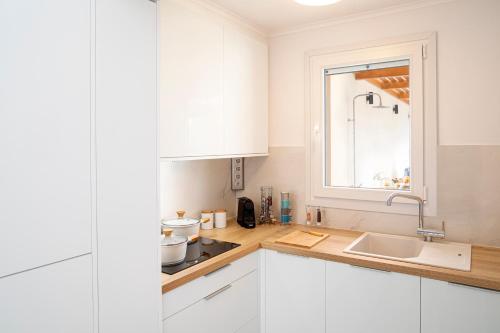 伊莱恩ETHOS Luxury Home - Seaview Villa with Hot-Tub!的厨房配有白色橱柜、水槽和窗户。