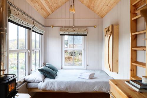 巴拉特Unique tiny house with wood fired roll top bath in heart of the Cairngorms的一间设有床铺的卧室,位于带窗户的房间内