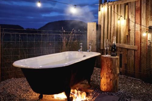 巴拉特Unique tiny house with wood fired roll top bath in heart of the Cairngorms的围栏旁的浴缸