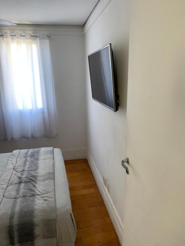 瓜鲁柳斯Quartos Vila Augusta/Guarulhos的卧室配有壁挂式平面电视。