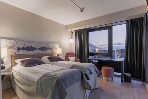 特罗姆瑟特罗姆瑟斯堪迪豪华酒店的一间卧室设有两张床、一张桌子和一个窗口。