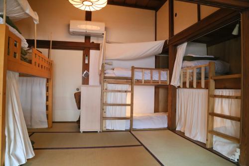 镰仓市Guest House Kamejikan -turtle time-的客房设有三张双层床和吊灯。