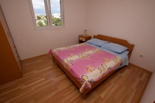 波弗加纳Apartments Dubrovnik Two的一间卧室配有一张带粉红色棉被的床和窗户