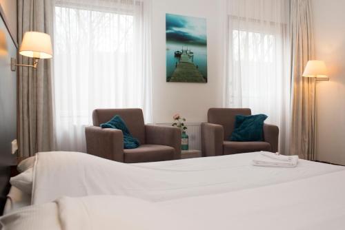 洛珀瑟姆Hotel Spoorzicht & SPA的酒店客房,配有一张床和两把椅子