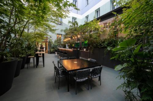 马德里珀蒂宫圣巴巴拉高科技酒店的一间设有桌椅的餐厅,种植了植物