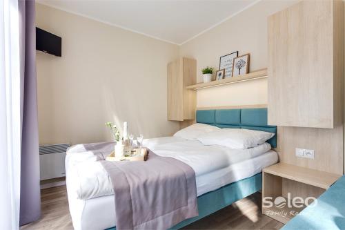 里沃SOLEO Family Resort的一间卧室配有一张白色的床和蓝色床头板