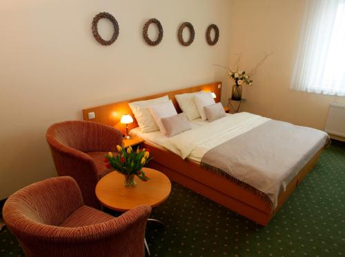 Grosspetersdorf吉普酒店 的一间卧室配有一张带两把椅子和一张桌子的床。