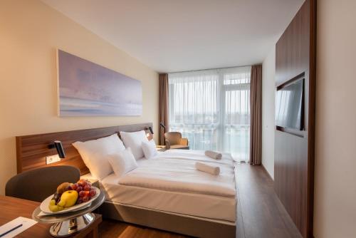 赫维兹Hunguest Hotel Panoráma的一间卧室配有一张床和一张桌子及一碗水果
