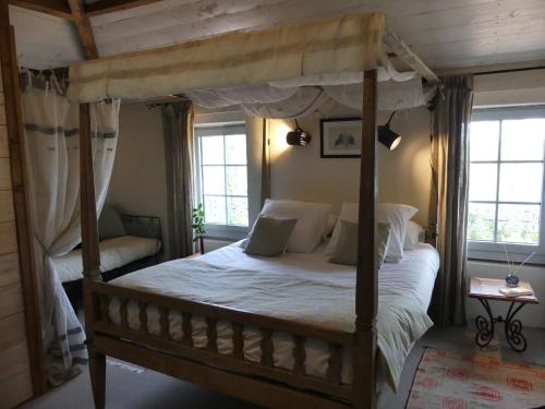 波讷地区帕朗提Domaine de l’Escuderia的一间卧室设有天蓬床和2个窗户