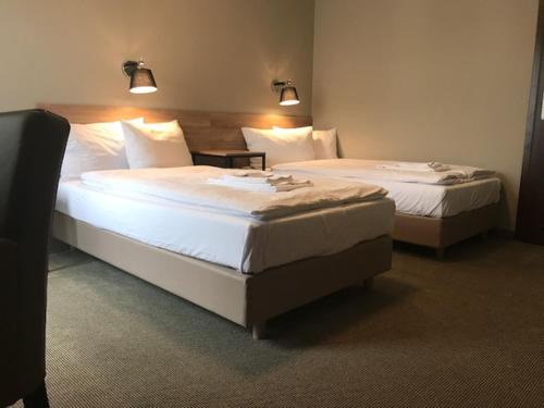 波兹南Comm Hotel Poznań Airport的配有白色床单的酒店客房内的两张床